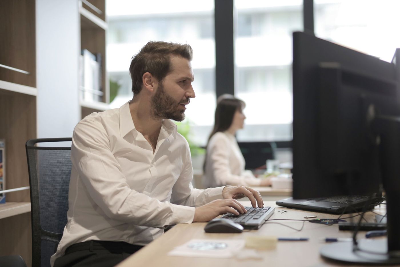 IT specialist working at a desktop computer in a bright office